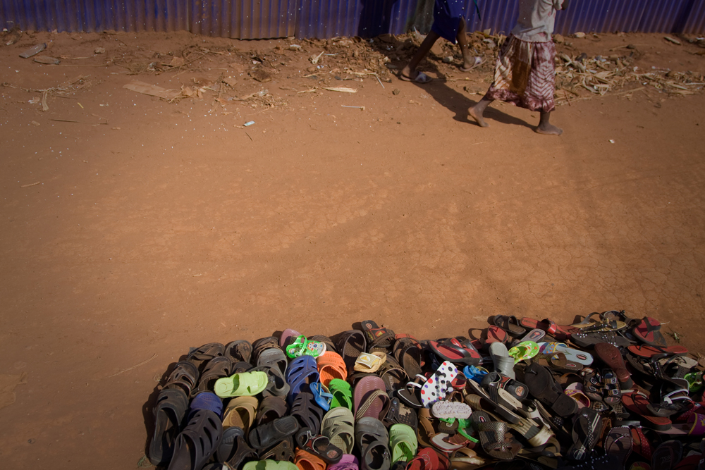 Children's bare feet walking by a pile of sandals