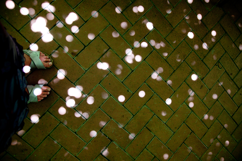 Spots of light falling onto someone's sandaled feet