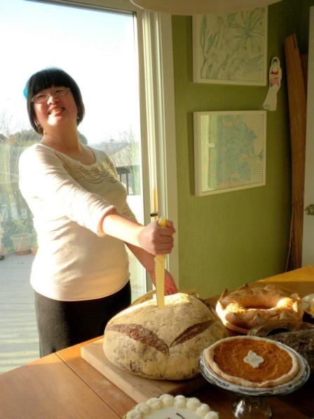 Lisa putting a bread knife into a giant loaf of bread