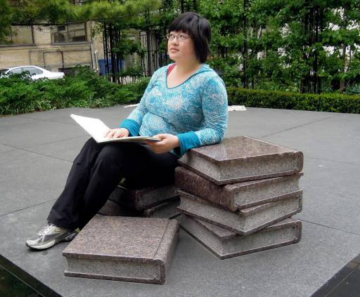 Lisa holding an open book on a stack of stone books
