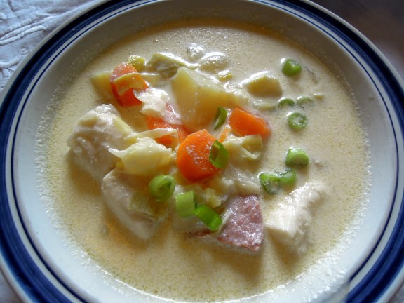 Fish chowder with visible pieces of fish, carrots, bacon, and green onions