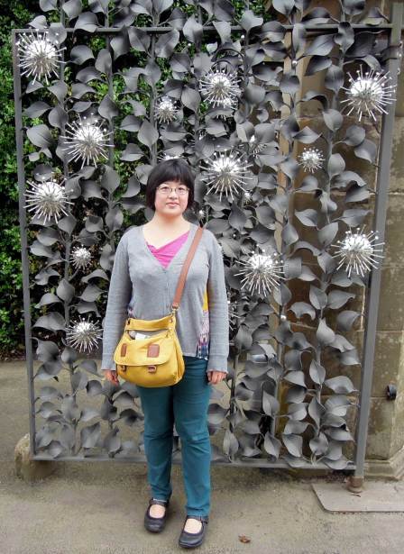 In front of one of the entrance gates, while waiting for the bus. I bought the cardigan and pants here in Edinburgh, though they're not local designs. Lisa in front of the silver flowers and matte metal leaves of the entrance gates.