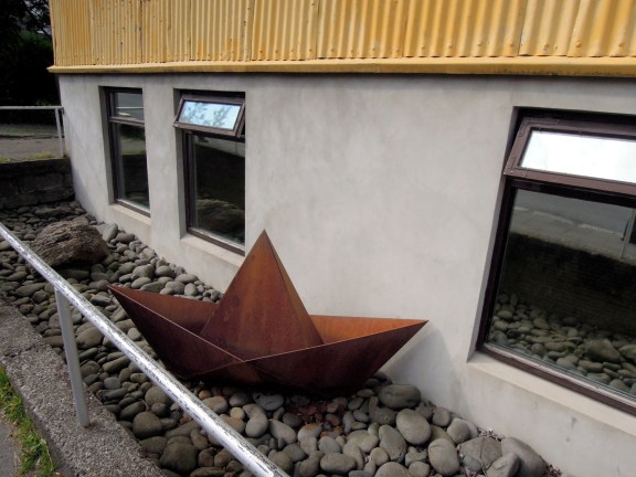 Copper "paper boat" sculpture in a yard