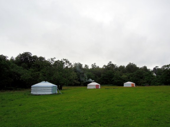 They look cozy and they are, though the inside smells like, well, yurt. Three yurts in a field and the center one has smoke rising from the chimney pipe