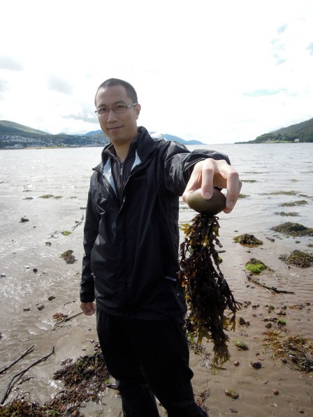 Erik holding a round rock with seaweed hanging down from it