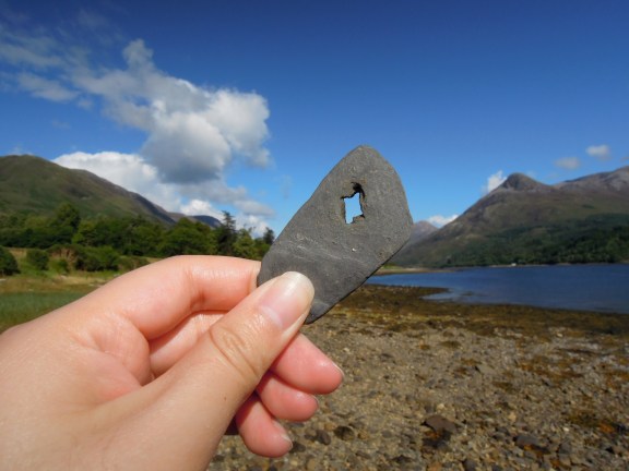 A flat stone with a funny-shaped hole in it, held up in Lisa's hand so you can see the sky through the hole