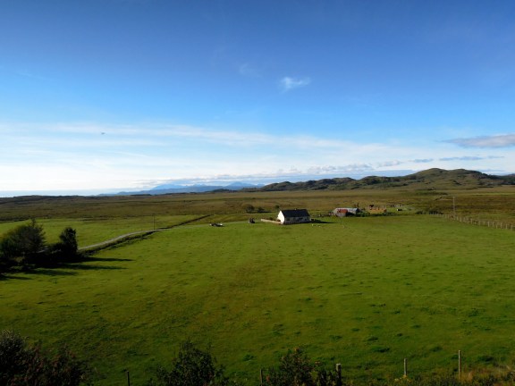 I wonder who lives here! Field with a little house and the ocean in the distance