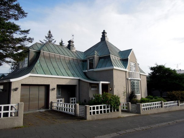 Grey house with grey-green roof in interesting almost pagoda-like shapes