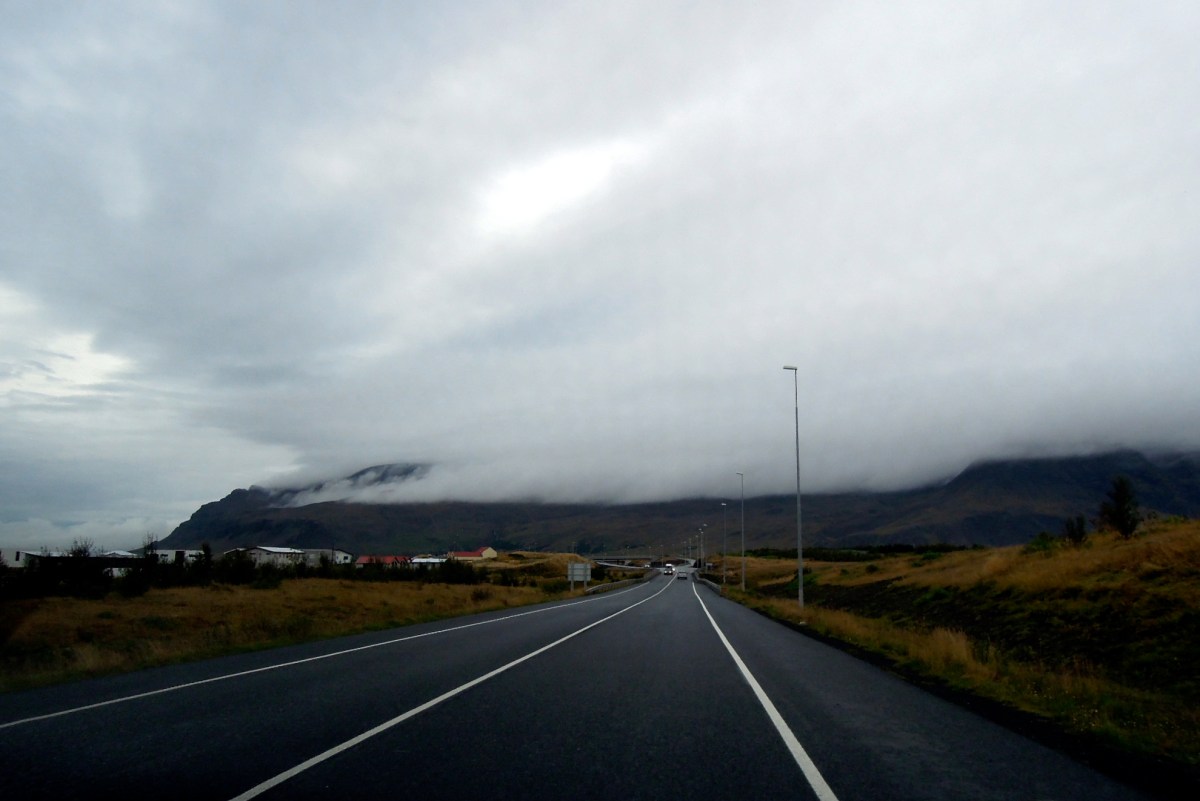 Highway with a cloud-topped mountain nearby