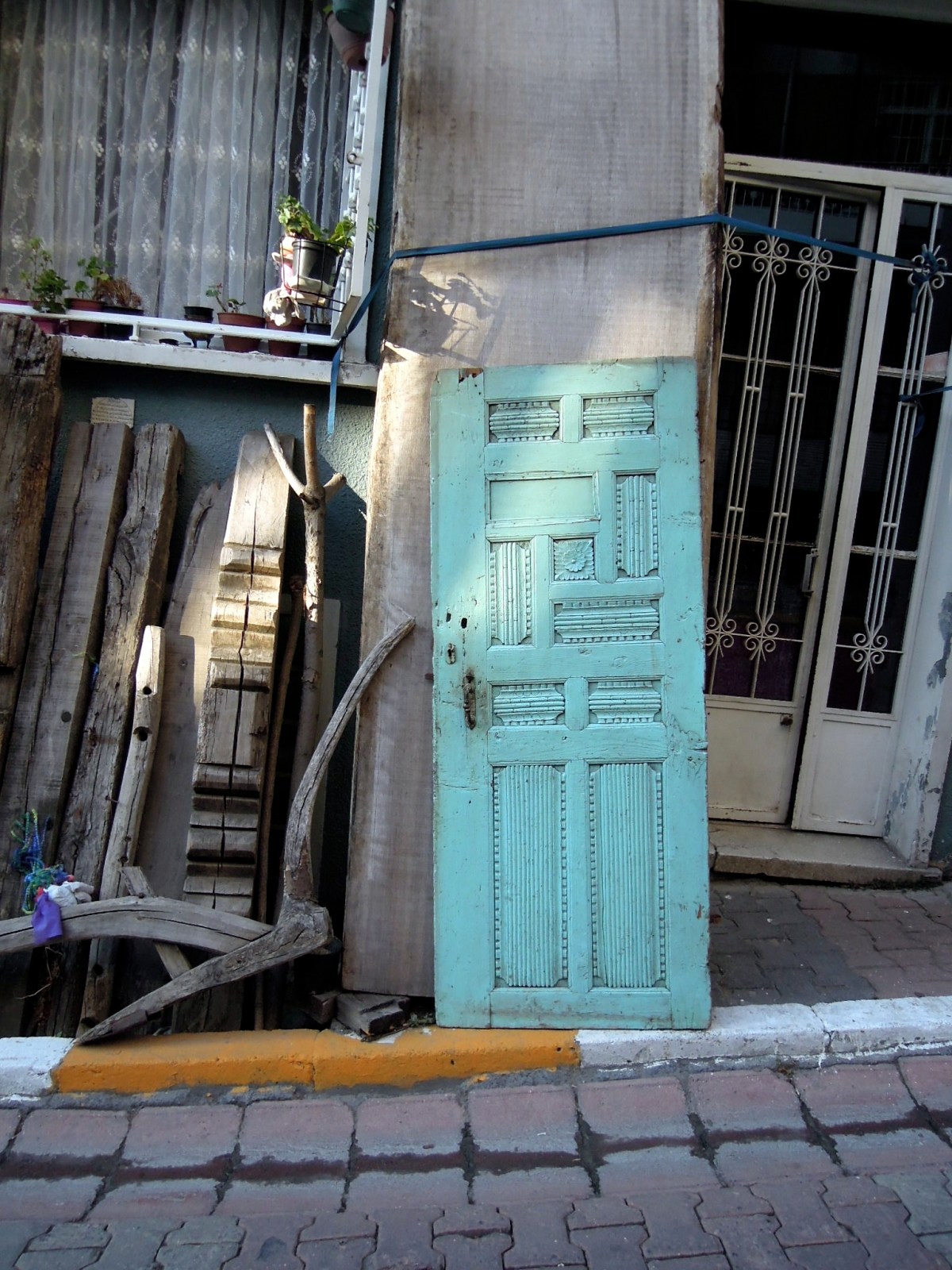 Carved turquoise door propped up against a building wall