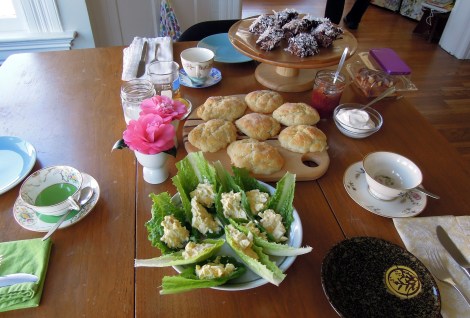 Breakfast table with lamingtons, scones, camellias, egg salad in lettuce leaves