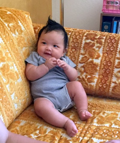Three-month-old Ada smiles from a vintage couch