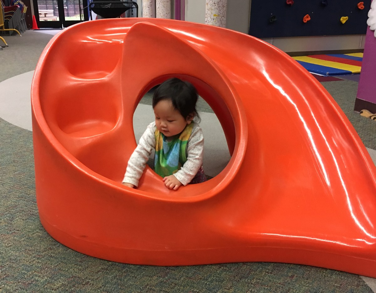 9-month-old Ada playing in an orange play structure