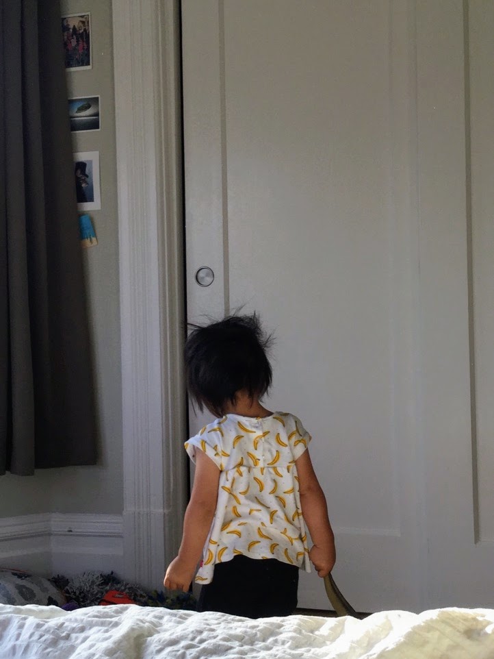 Messy-haired toddler dragging a toy dinosaur around by its neck