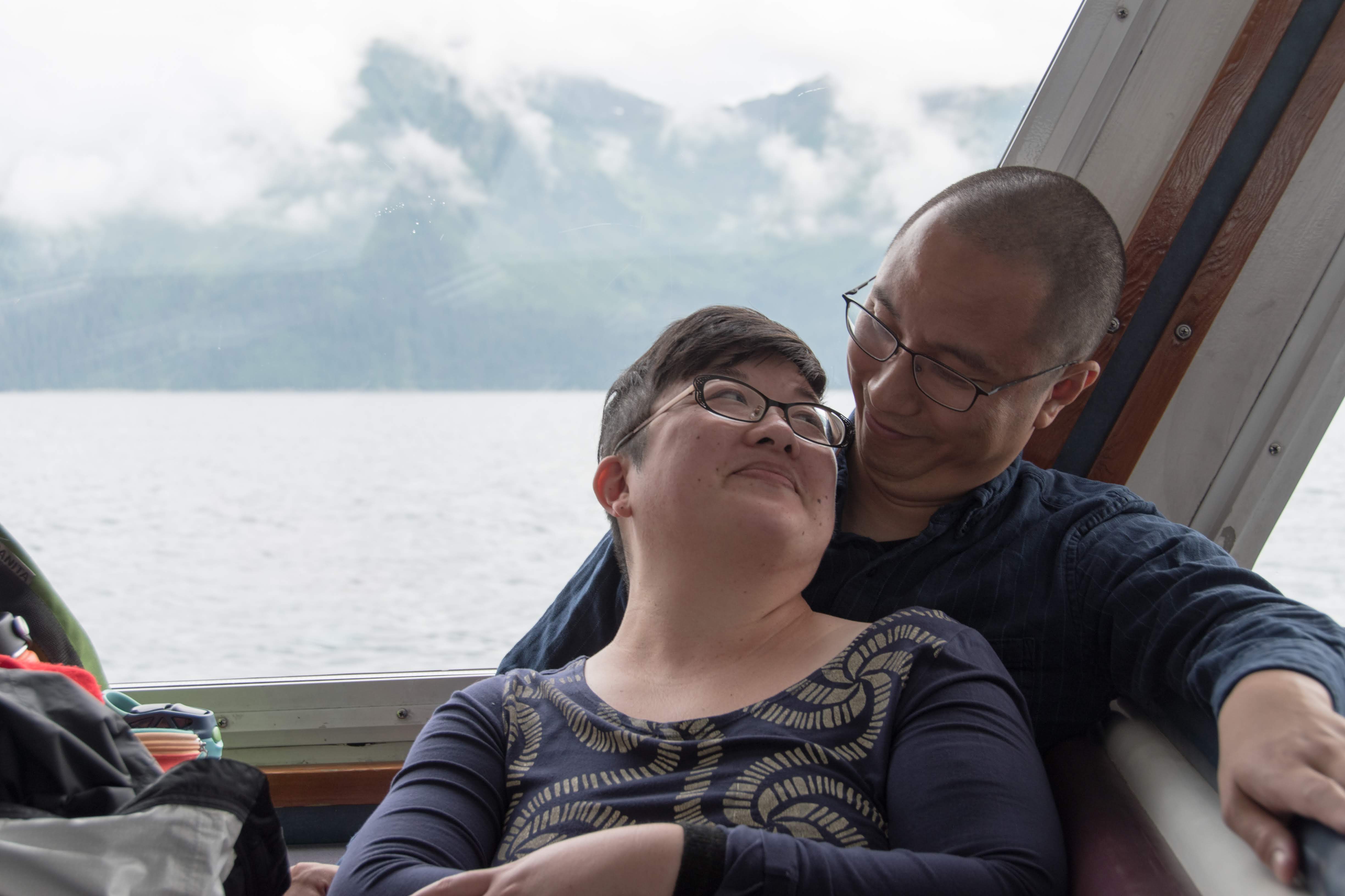 An Asian couple relaxes together on a a boat in Alaska.