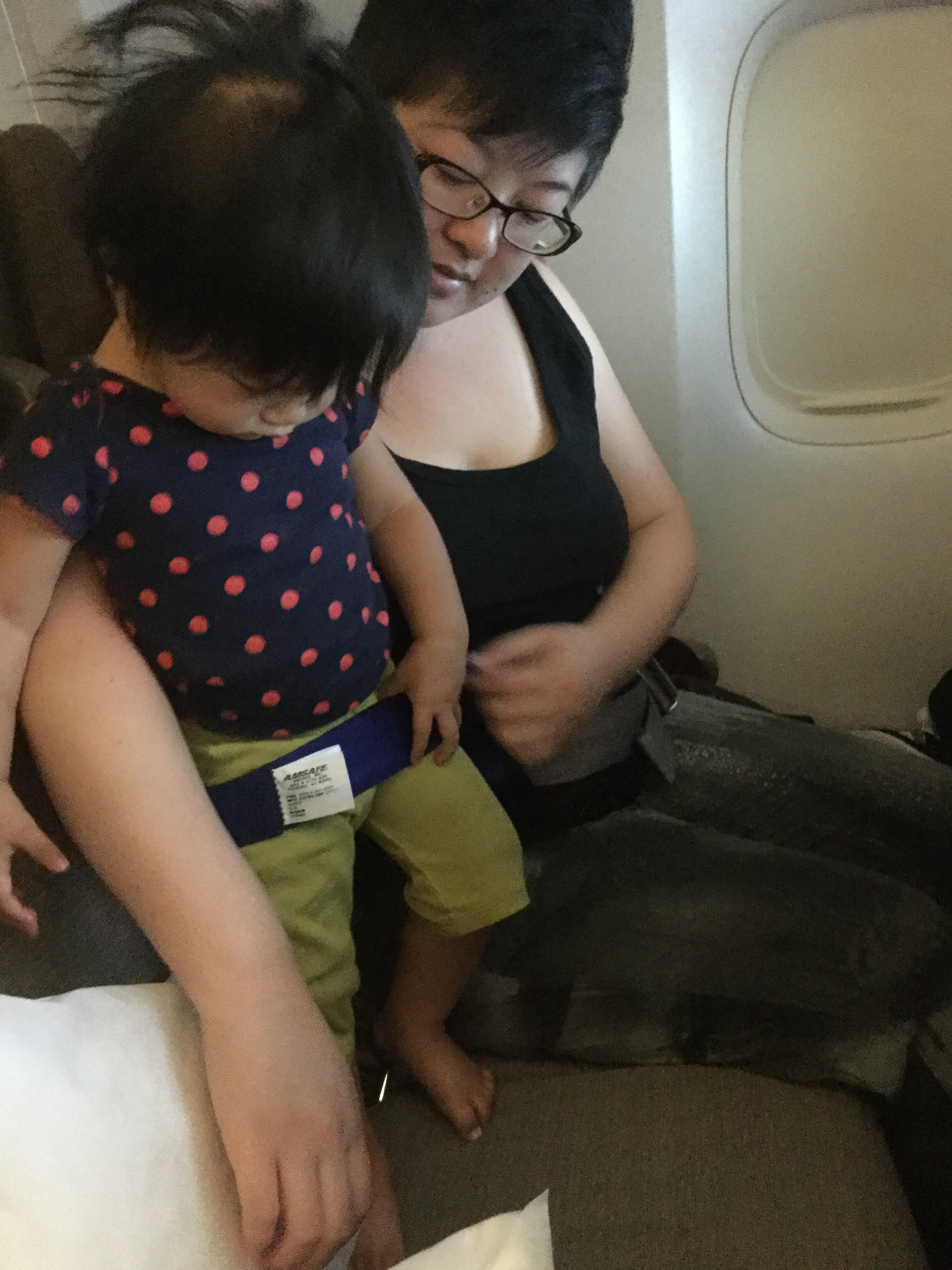 An Asian mother and small child in airplane seats