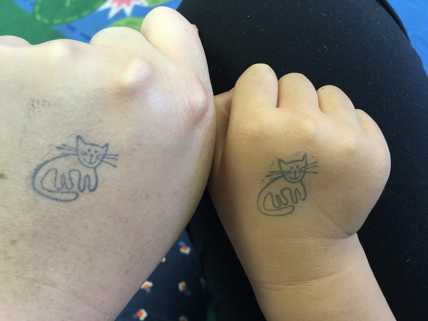 An adult and a kid's hand next to each other, both with a cat hand stamp
