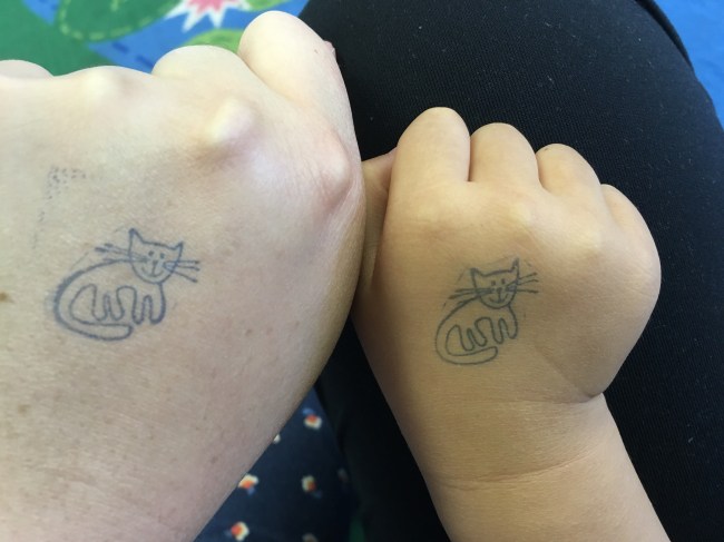 An adult and a kid's hand next to each other, both with a cat hand stamp