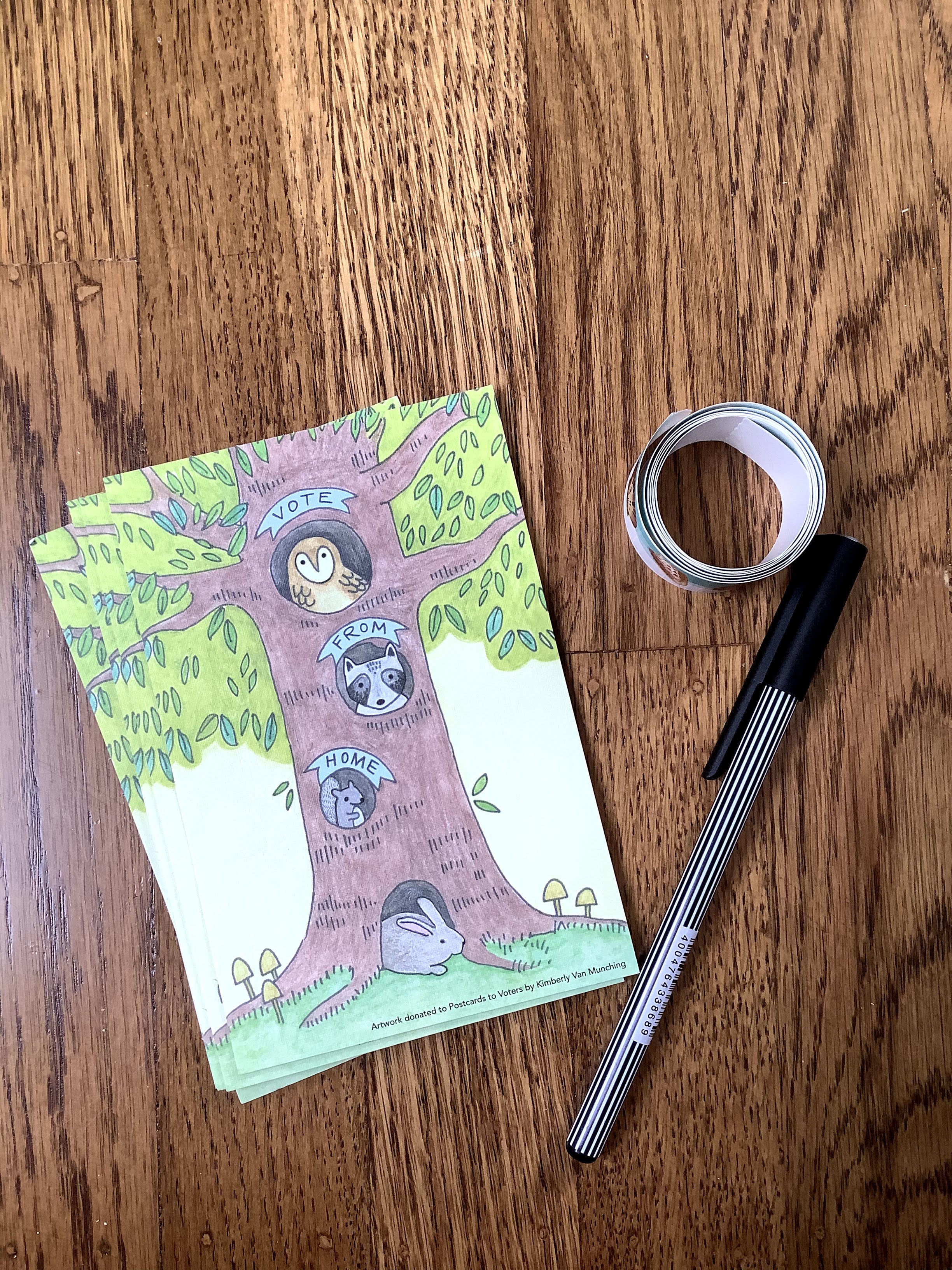 A pen, a coil of stamps, and a stack of identical postcards