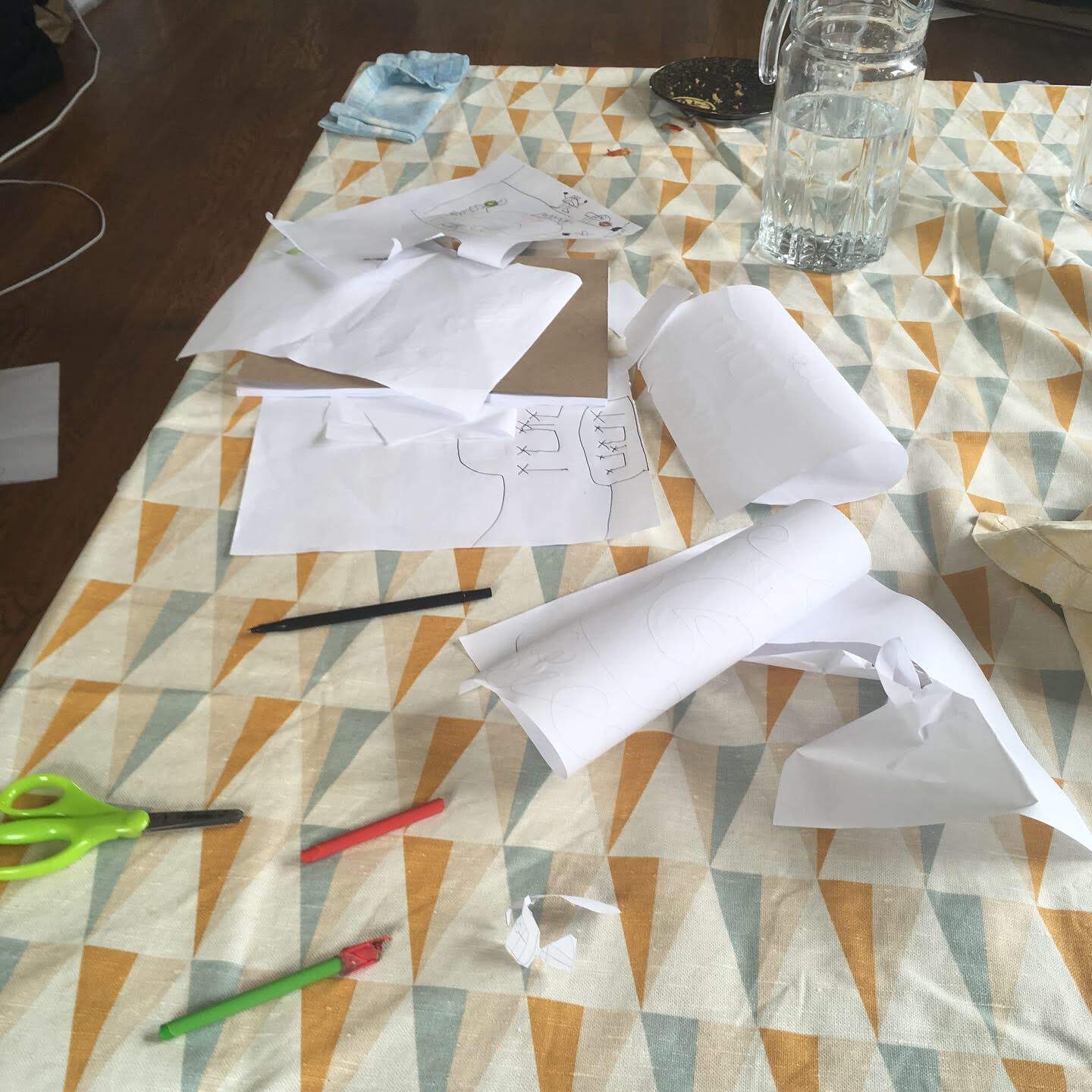 Tablecloth-covered table with kid art supplies all over it