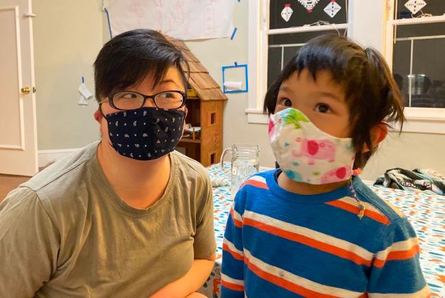 Short-haired East Asian American parent and young child with masks