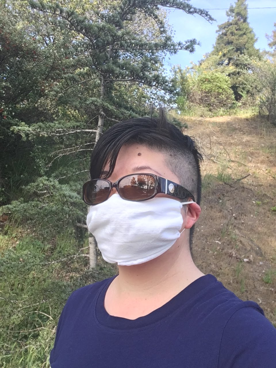 Short-haired Asian woman wearing sunglasses and a face mask improvised from a white hankie