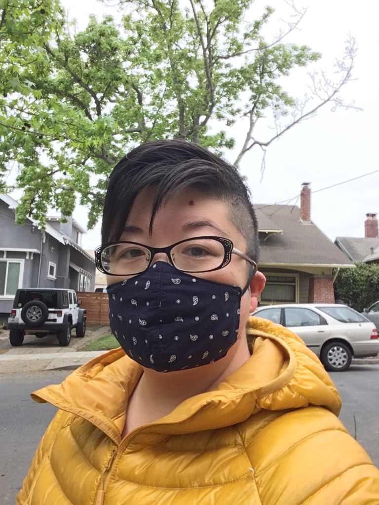 Asian American woman in short hair and glasses, wearing a navy blue face mask