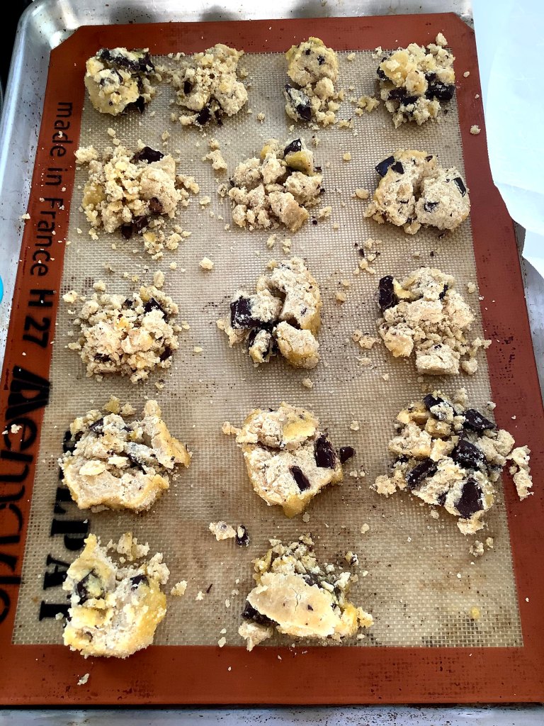 Crumbly chocolate chunk shortbread rounds on a baking sheet