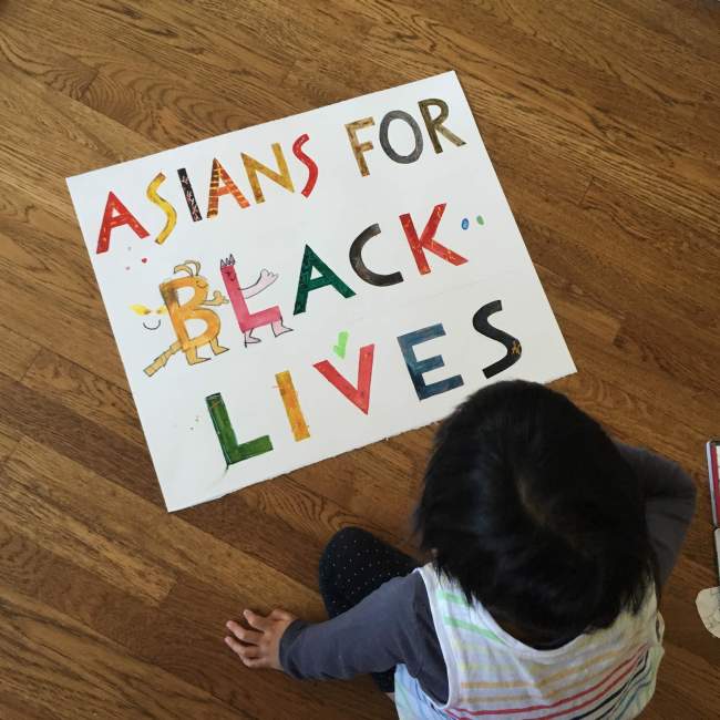 Dark-haired 4yo viewing an ASIANS FOR BLACK LIVES hand-painted sign