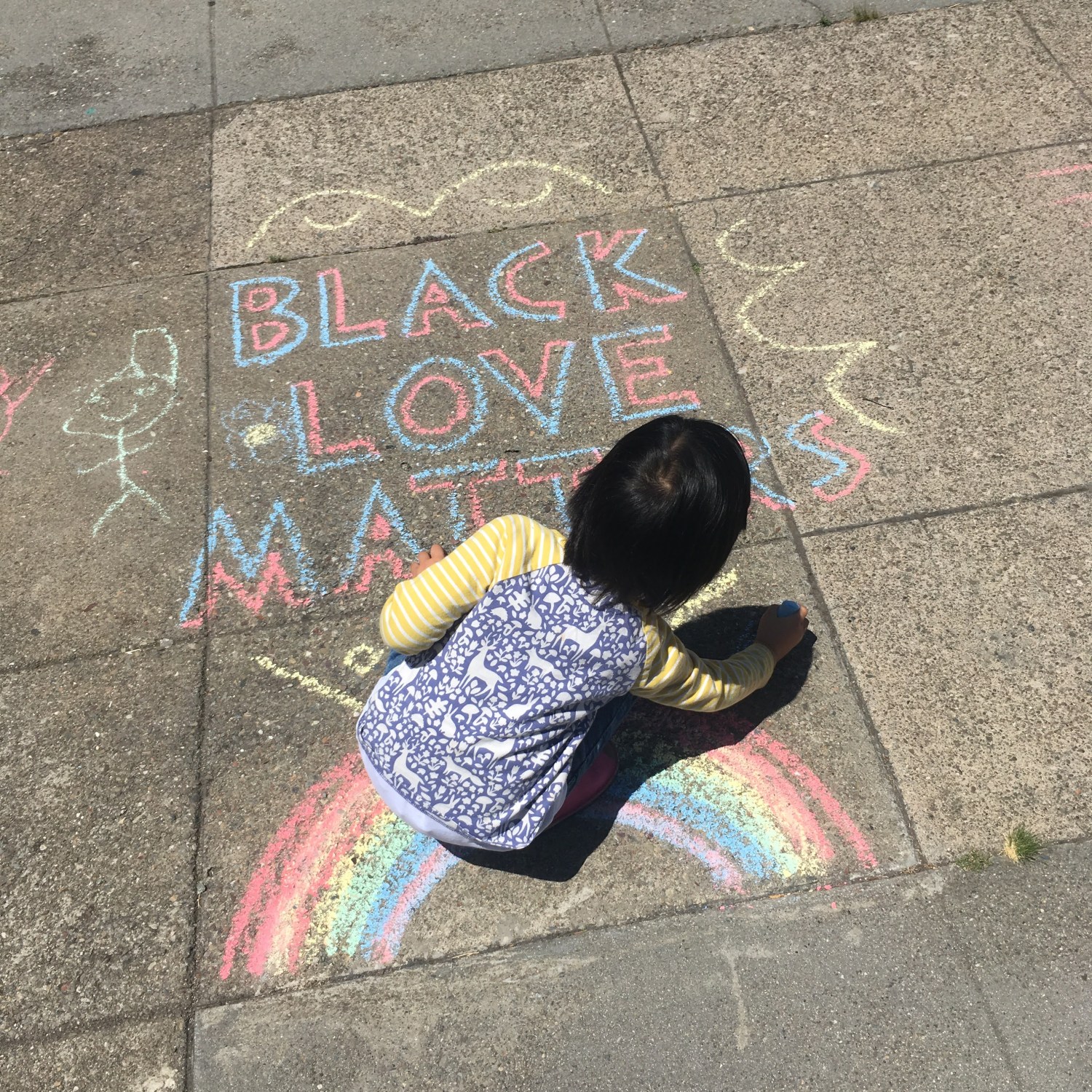 Small child decorating a sidewalk message, BLACK LOVE MATTERS