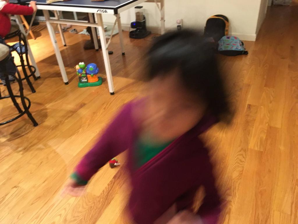 A young dark-haired child runs through a house, blurred with motion